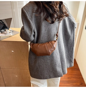 Detailed close-up of dark brown leather croissant bag with fine stitching and shoulder strap