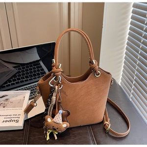 Detailed shot of brown suede bucket bag with knotted handle and cute plush charms