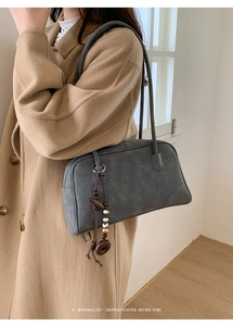 Detail of dark grey retro shoulder bag with wood bead charm on minimalist camel coat
