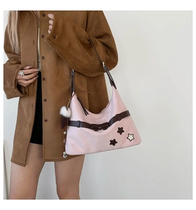 Detail of light pink hobo bag with brown bow strap, star patches and white pompom charm