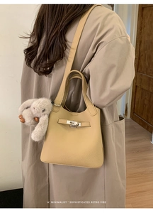 Detail of khaki leather bucket bag featuring silver clasp and plush rabbit pendant
