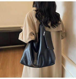 Detail of black large capacity shoulder tote bag featuring a decorative strap knot