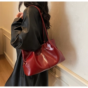 Fashionable bordeaux red pleated tote bag styled with a leather coat for a modern commute