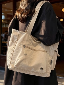 Minimalist beige oversized nylon tote bag with multiple pockets and wide shoulder straps
