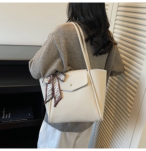 Detail of off-white tote bag with lychee texture and silk scarf on a book shelf