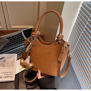 Detailed view of a brown vintage bucket bag with a cute plush bear charm and handle