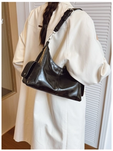 Detail of black semi-moon PU leather bag with side pocket and silver hardware