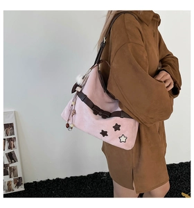 Detailed close-up of pink suede shoulder bag with star patches and bow decoration