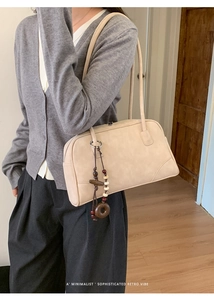 Detail view of cream suede shoulder bag with retro wooden beads and minimalist handle