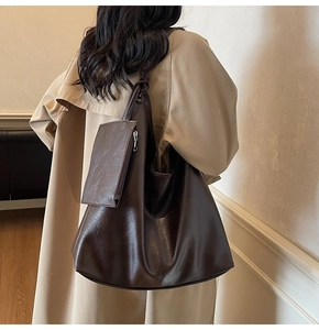 Model showing large dark brown tote bag with small pouch over a khaki trench coat