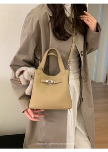 Detail of beige lychee leather handbag with metal twist lock and cute elephant charm