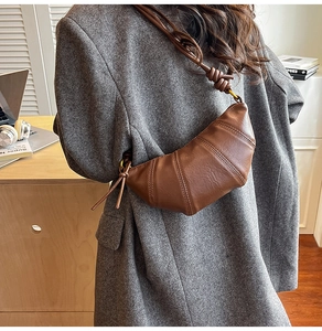 Detail of dark brown leather croissant bag with knotted strap shown on person