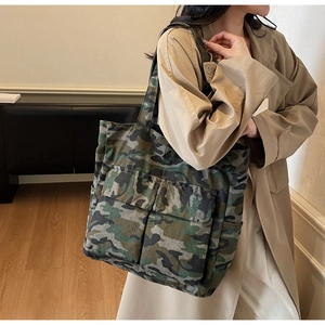 Detail of camouflage canvas tote bag featuring dual front pockets and durable shoulder strap