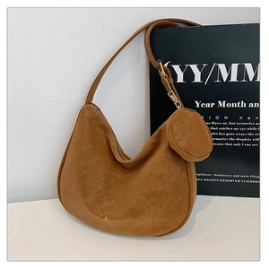 Detail of brown matte suede crescent shoulder bag featuring gold JV logo and round coin purse