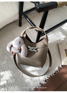 Detail of retro leather bucket bag with silver cross latch and grey plush rabbit charm
