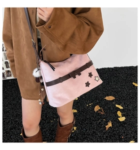 Detail of pink suede shoulder bag featuring a dark brown bow and star patches
