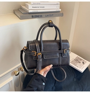 Dettaglio borsa vintage in pelle cerata con cuciture a contrasto e fibbie dorate