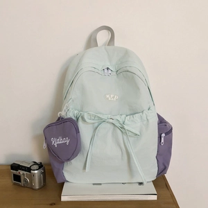 Detailansicht des minzgrünen Rucksacks mit violetter Tasche und herzförmigem Anhänger