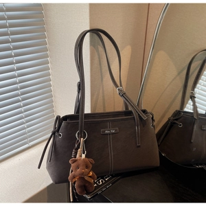 Detail of dark coffee brown tote bag with contrast stitching and teddy bear charm