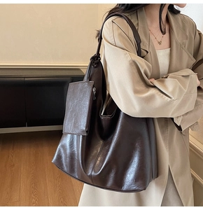Detail of dark brown leather tote bag showing large capacity and soft texture on shoulder