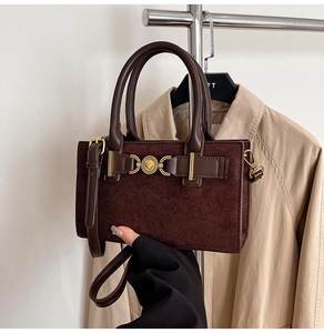 Detail of coffee brown crossbody bag with gold heart buckle and suede texture