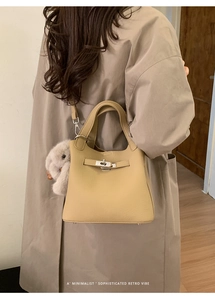 Detail of beige lychee leather bag with metal twist lock and plush rabbit charm