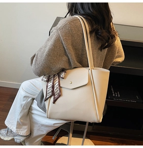 Detail of cream tote bag with lychee grain leather, gold buckle, and stylish silk scarf