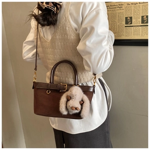 Detail of a brown suede bucket bag with leather trim and a cute plush bunny charm