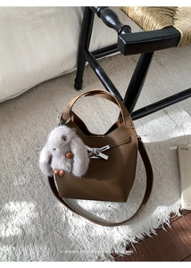 Detail of brown litchi pattern leather bucket bag with silver bow clasp and bunny charm