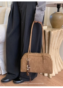 Detail of retro brown suede Boston bag with wooden bead charm and long dual handles