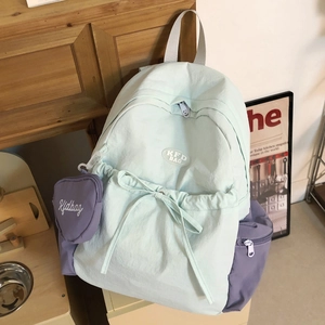 Detail von hellblauem und violettem Nylon-Rucksack mit Schleife und Herztasche