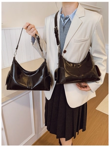 Polished black leather crescent bag with side pockets and adjustable shoulder strap