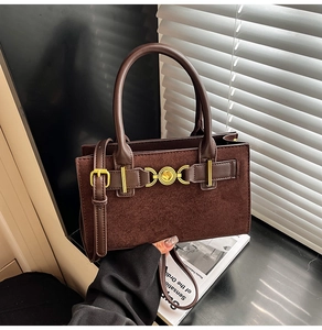 Detail of vintage dark brown handbag with gold heart buckle and leather texture