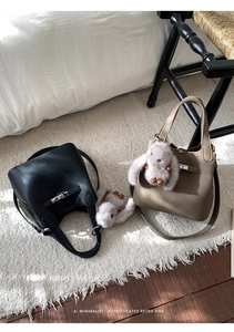 Macro shot of black and khaki leather bucket bags with metal buckles and plush rabbit charms