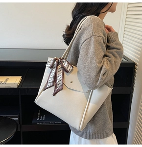 Close-up of creamy white tote bag with lychee texture and silk scarf decoration