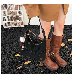 Detail of black nylon tote bag featuring bow star patch and fluffy charm accessory