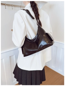 Detail view of the black high-gloss shoulder bag with a side flap pocket and silver buckle