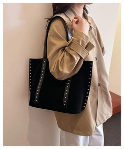 Close-up of black suede tote bag with vertical silver rivet studs and retro strap detail
