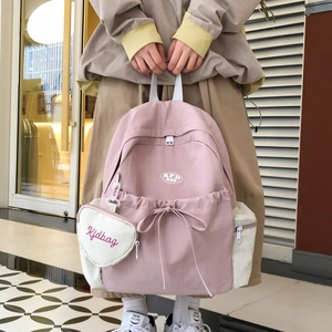Detail eines rosa Canvas-Rucksacks mit Schleifenzug und Mini-Herz-Anhänger-Tasche