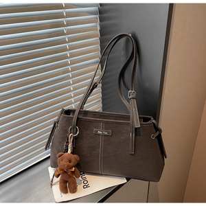 Detail of dark coffee matte shoulder bag with cute bear charm and adjustable straps