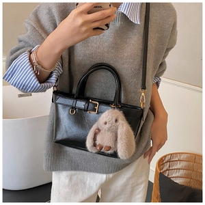 Detail of black vintage bucket bag with metal buckle and cute long-eared rabbit charm