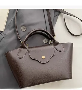 Detail of dark brown pebble leather bucket bag with gold buckle on office suit background