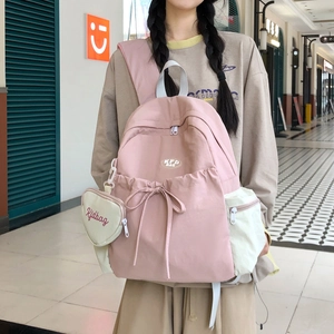 Rosa Schulrucksack-Detail mit Seitentasche, Herzanhänger und dekorativem Schleifendetail