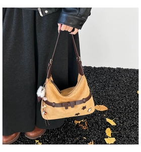 Detail of camel suede tote bag with brown leather straps and white faux fur pompom charm