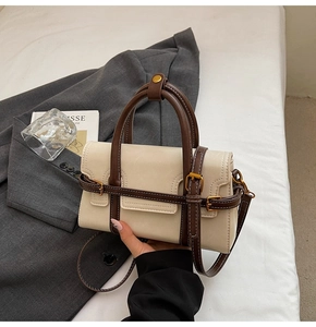 Dettaglio di una borsa a tracolla vintage crema e marrone con fibbie e manico