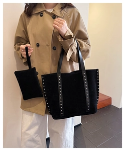 Detail of black suede tote bag with silver studs and matching pouch set on a model