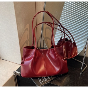 Detailed macro view of pleated dark red leather tote bag with glossy texture and slim straps