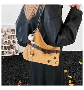 Detail of yellow suede shoulder bag with brown leather bow and star pattern charms