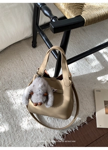 Detail of tan pebble leather bucket bag with silver twist lock and plush rabbit charm