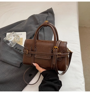 Dettaglio borsa a mano retrò in pelle marrone con cuciture bianche e fibbia dorata